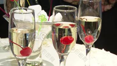 装饰精美的香槟酒杯摆在桌子上，里面有一个红樱桃，一个婚礼庆典。